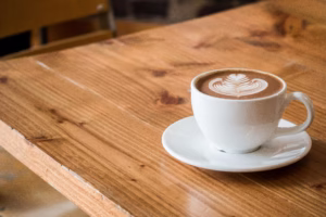 A cup of coffee on a wooden table in a cosy café, symbolising a calming moment amidst everyday anxieties.